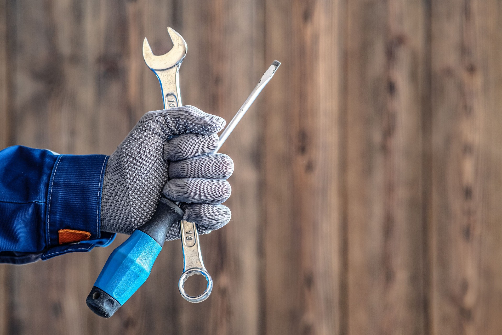 Locksmith maintenance work. The master holds a key and a screwdriver in his hand.